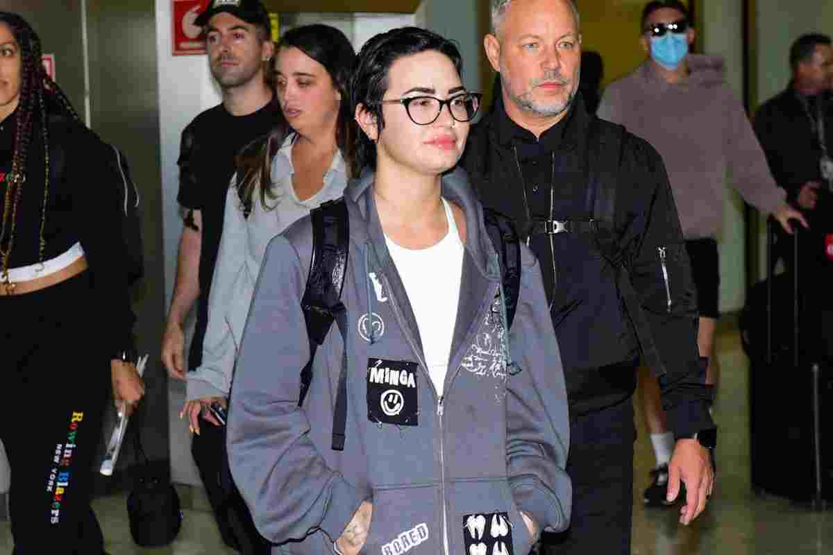 Demi Lovato vestida com jaqueta cinza e óculos