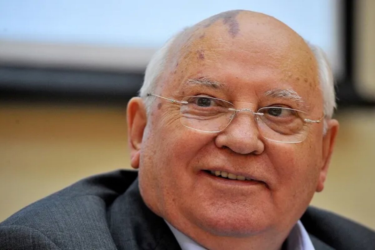 Mikhail Gorbachev sorrindo, de terno, olhando para o lado