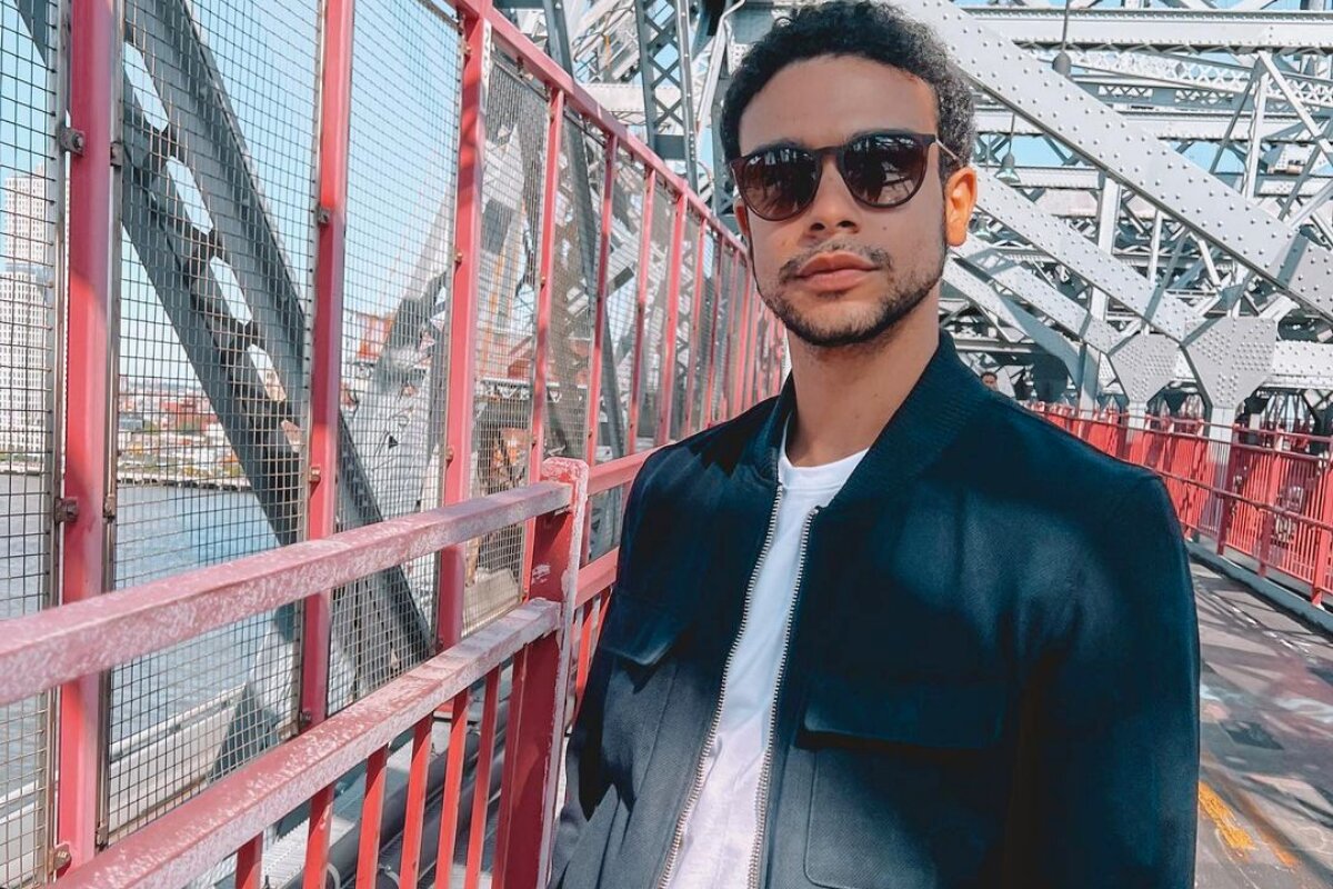 Sérgio Malheiros de óculos escuros, jaqueta preta e camisa branca, na Brooklin Bridge, em Nona Iorque