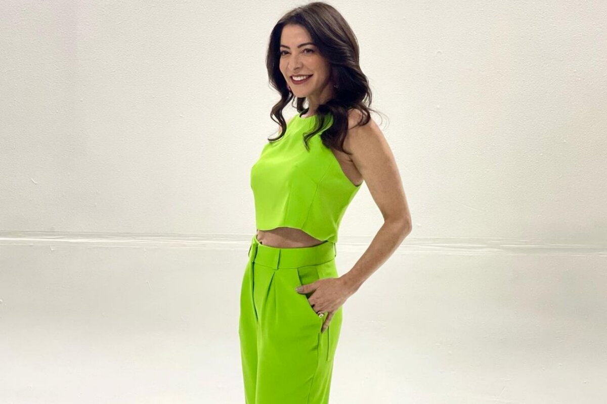 Ana Paula Padrão de calça e blusa verde, de barriga de fora, com as mãos no bolso