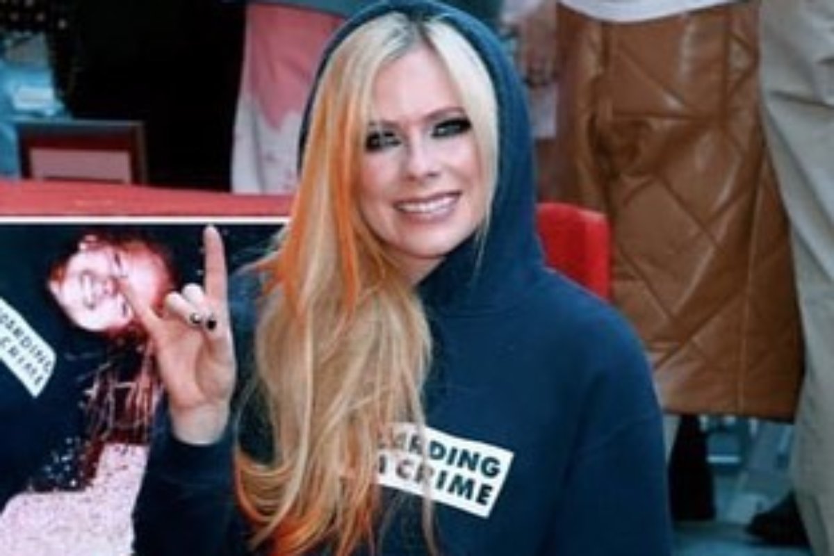 avril lavigne posando sorridente e com gesto de rock em calçada da fama