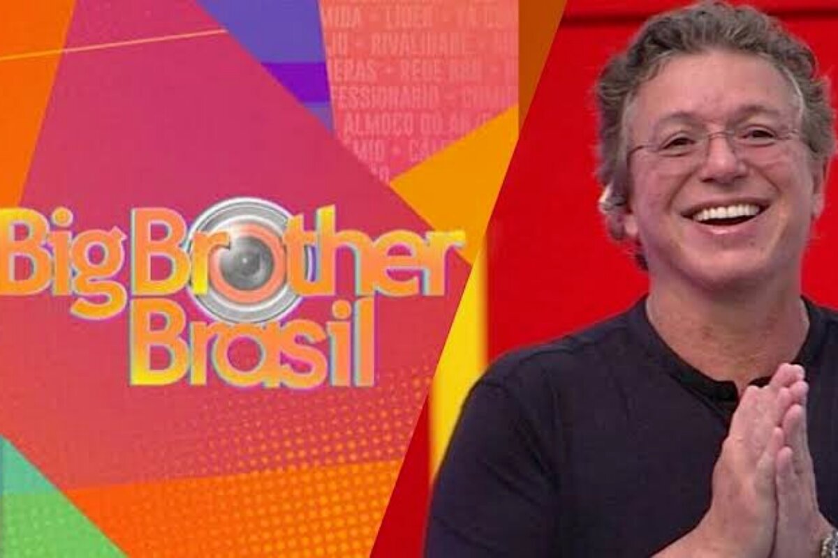 Boninho sorrindo, de camisa preta, na frente da logo do BBB