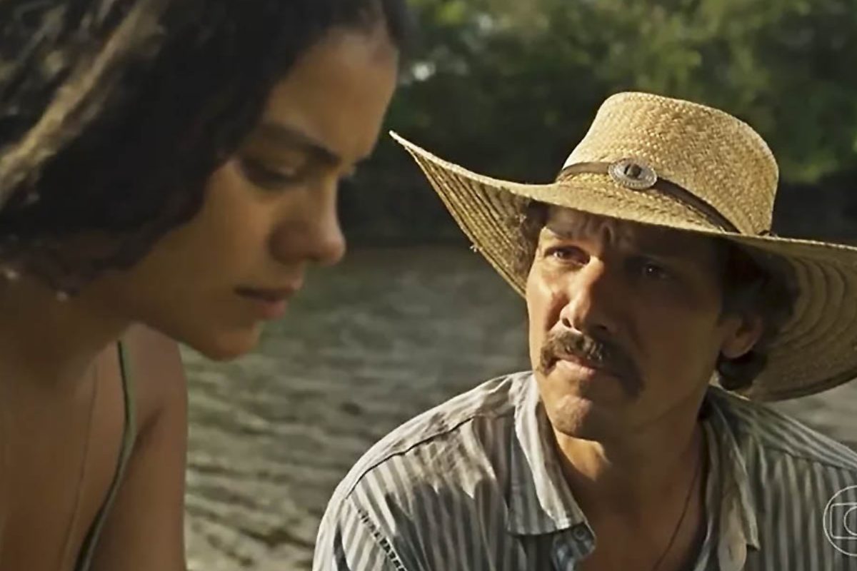 Muda (Bella Campos) e Tibério (Guito) conversam sério à beira do rio, em Pantanal