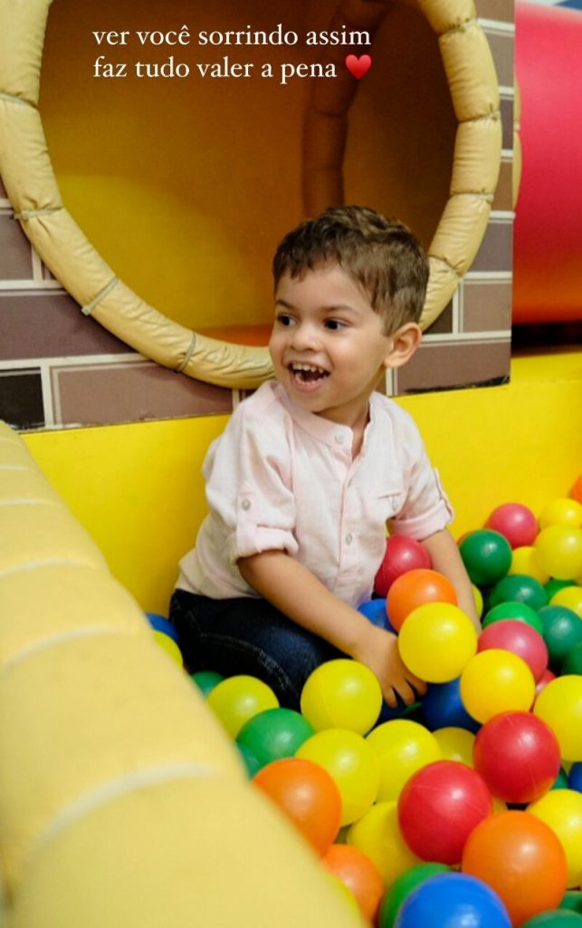 Leo de camisa branca brincando na piscina de bolas coloridas